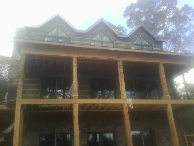 Dormers and porch framing on a large log home under construction — Roof Coating work by our crew in Morton